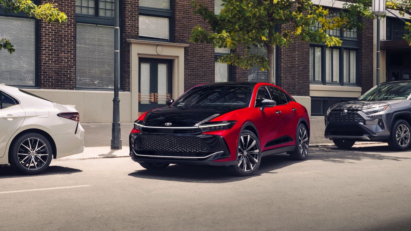 A red and black Toyota Crown leaving a parallel parking space