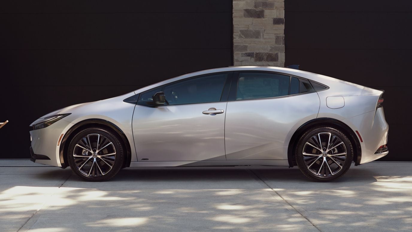 A silver Toyota Prius in profile, parked in front of a garage