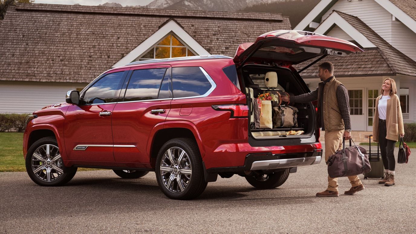 A couple loading up the trunk of a red Toyota Sequoia