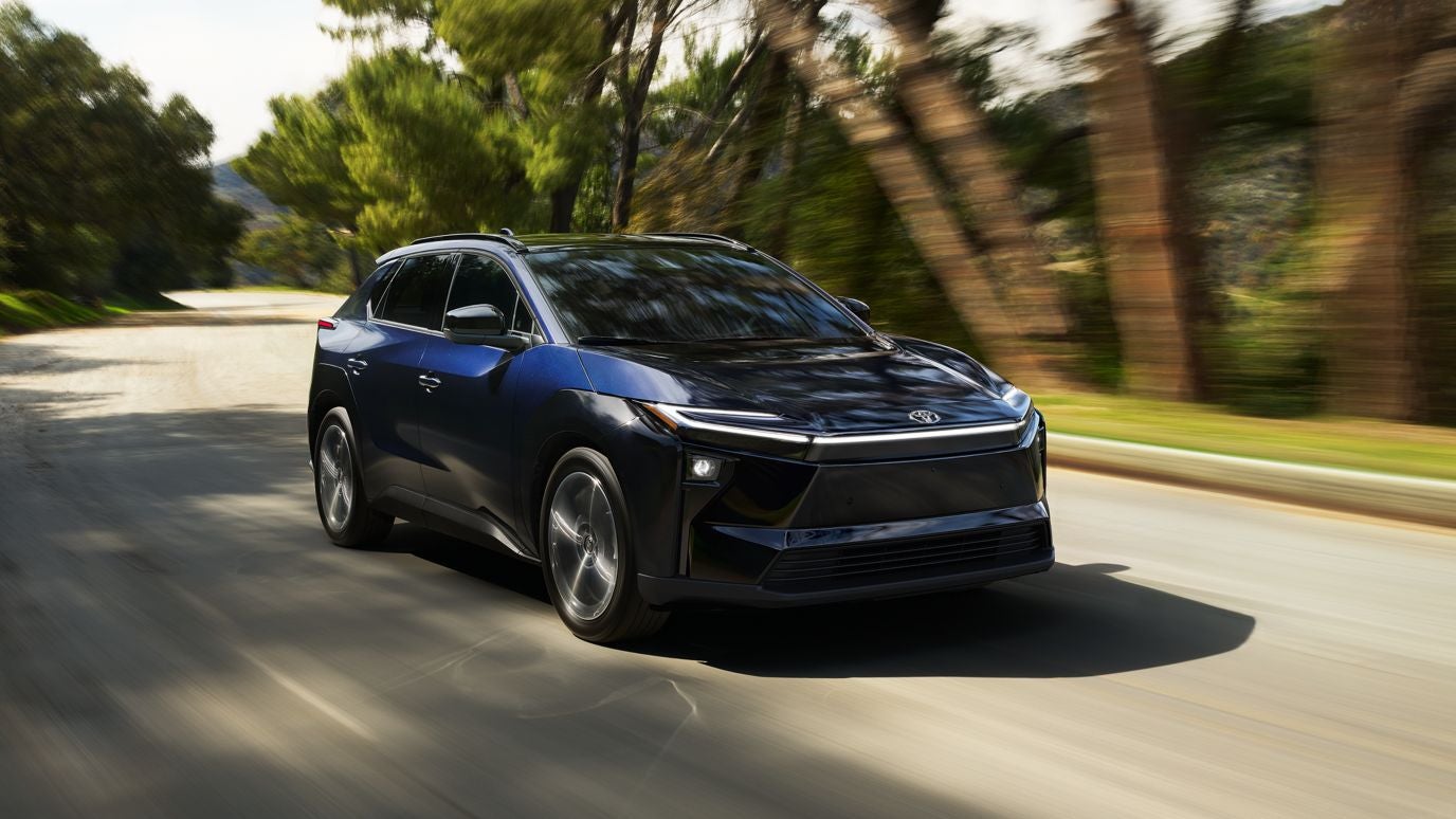 A blue Toyota bZ driving down the road