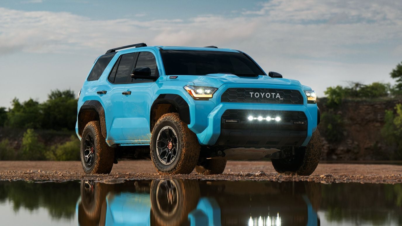 A light blue Toyota 4Runner parked by a lake in a clearing