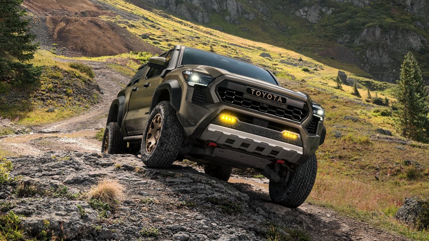 A Toyota Tacoma driving on a dirt road on a hillside