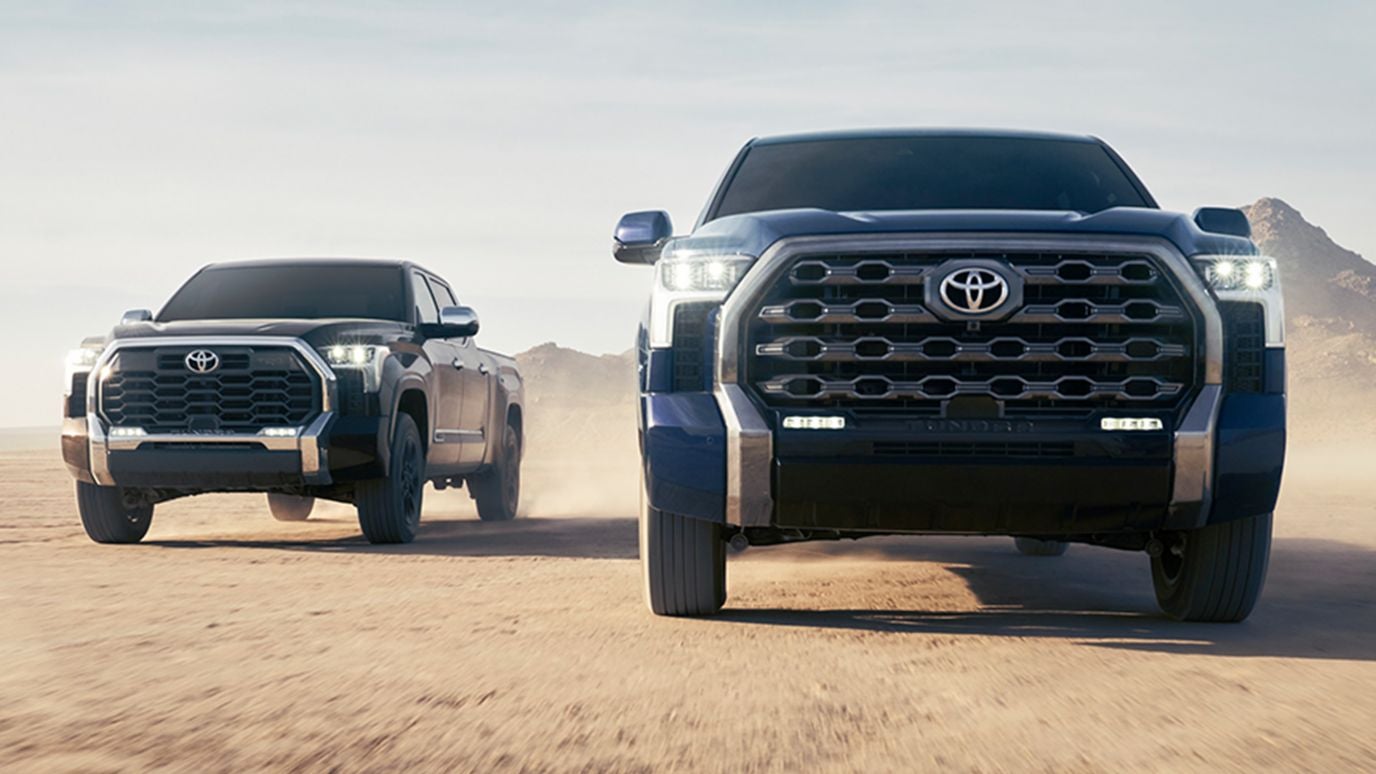 A pair of blue Toyota Tundras driving through a desert