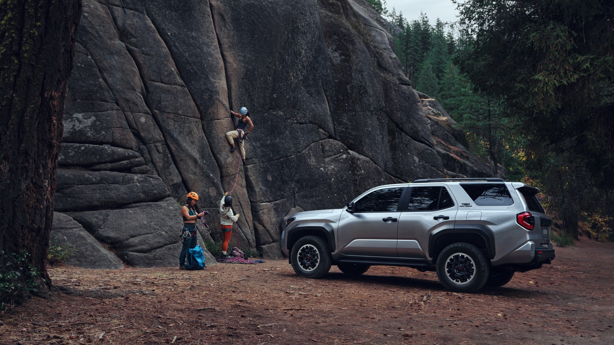 A silver 2025 Toyota 4Runner parked by a cliffside where people are rock climbing