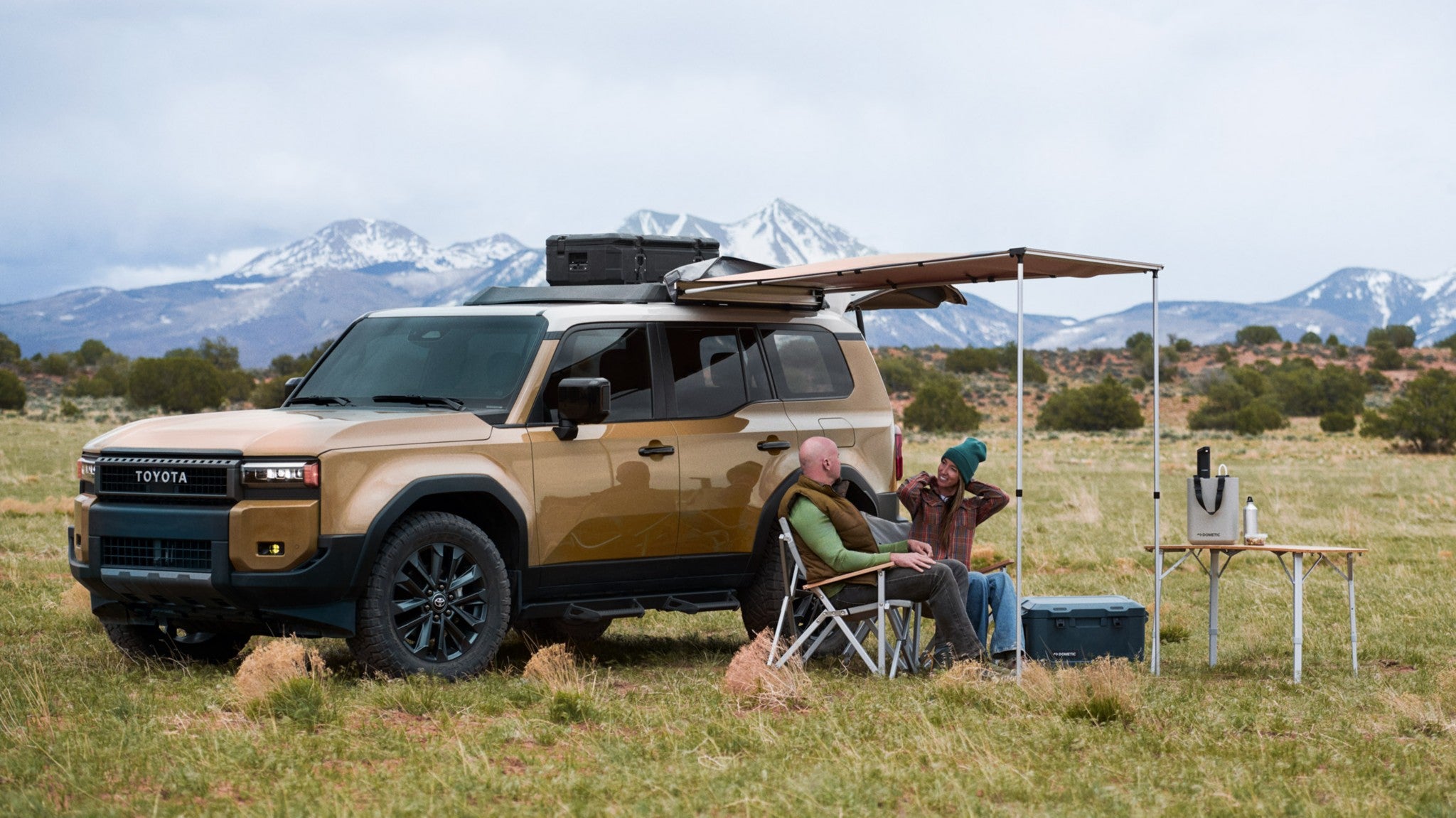 A brown 2025 Toyota Land Cruiser parked in a field and being used for camping