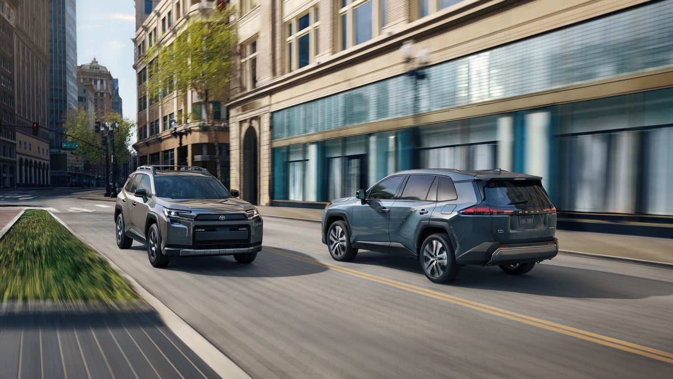 A blue and gray Toyota RAV4 driving by each other in a city
