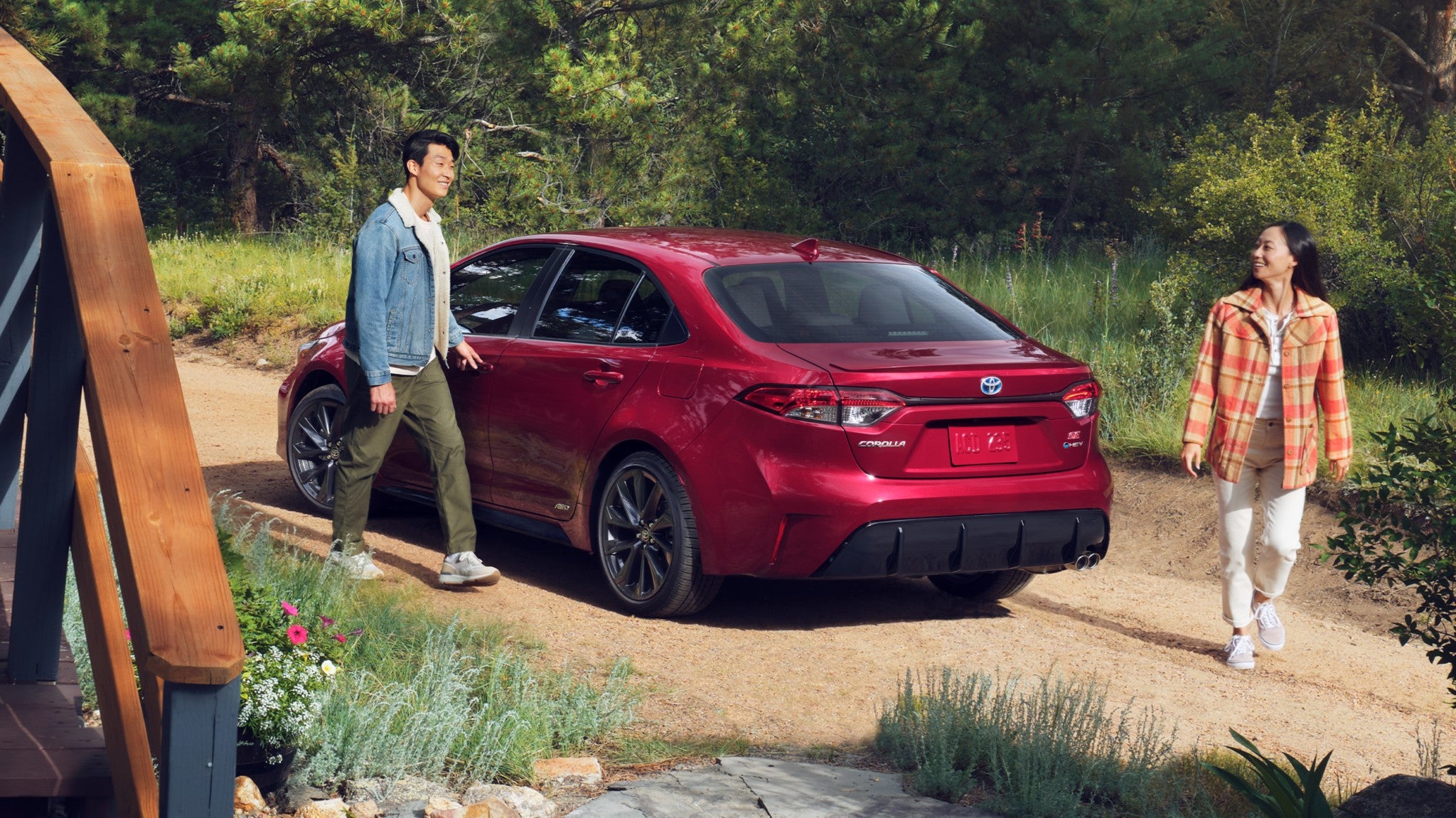 A red Toyota Corolla parked on a trail with a couple walking away from it