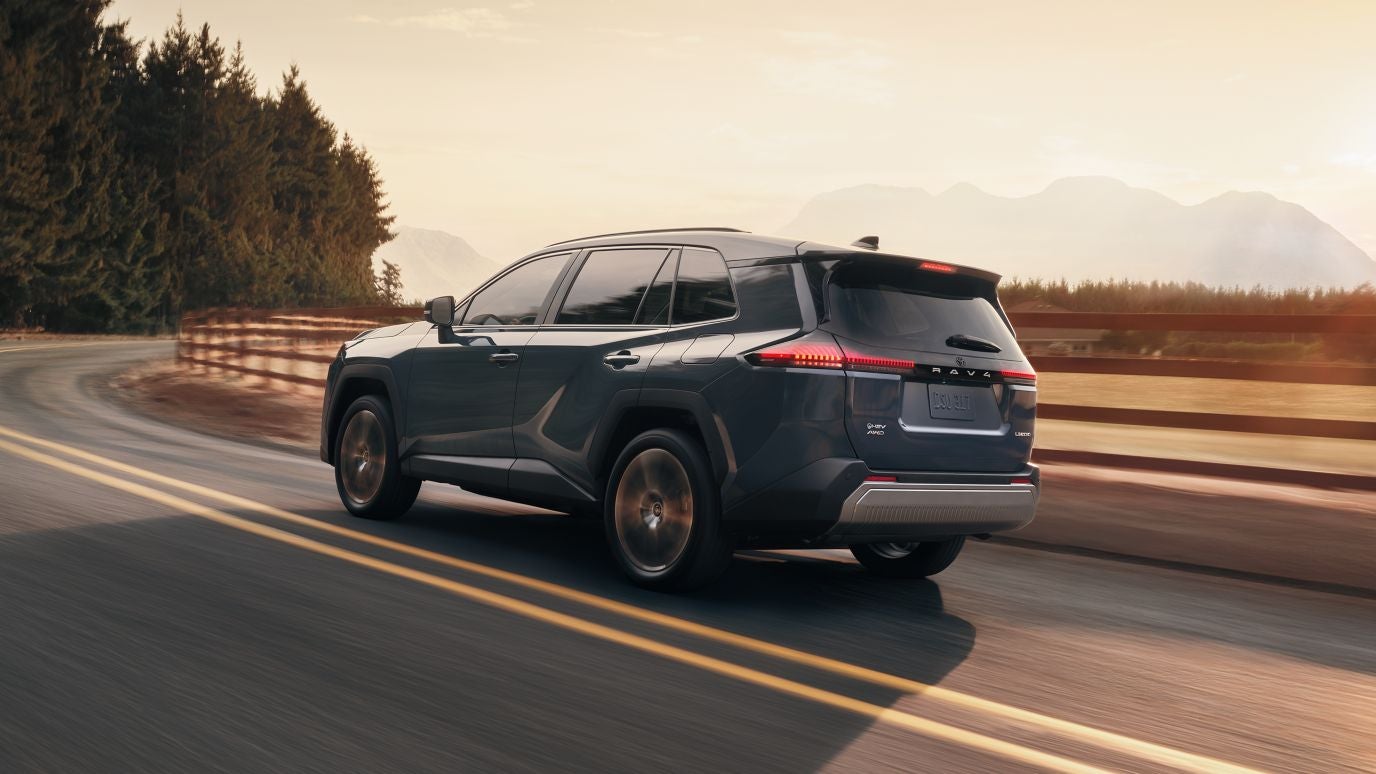 A blue Toyota RAV4 driving around a bend on the road.