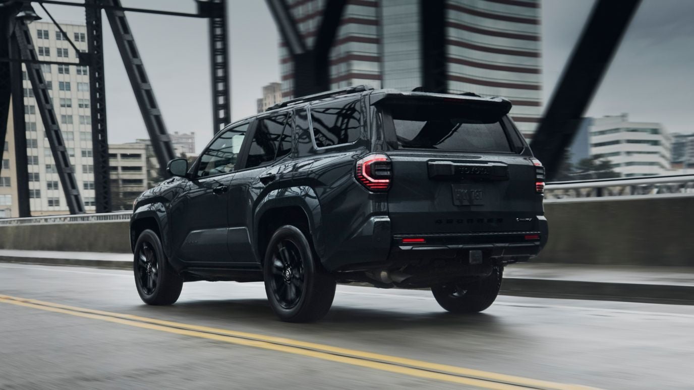 A black Toyota 4Runner driving over a bridge into a city