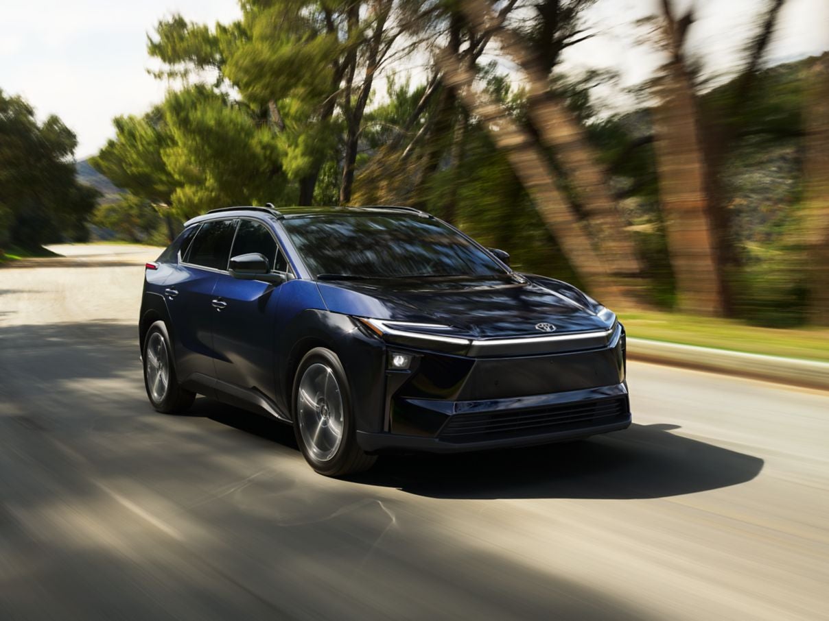 A blue Toyota bZ driving down the road