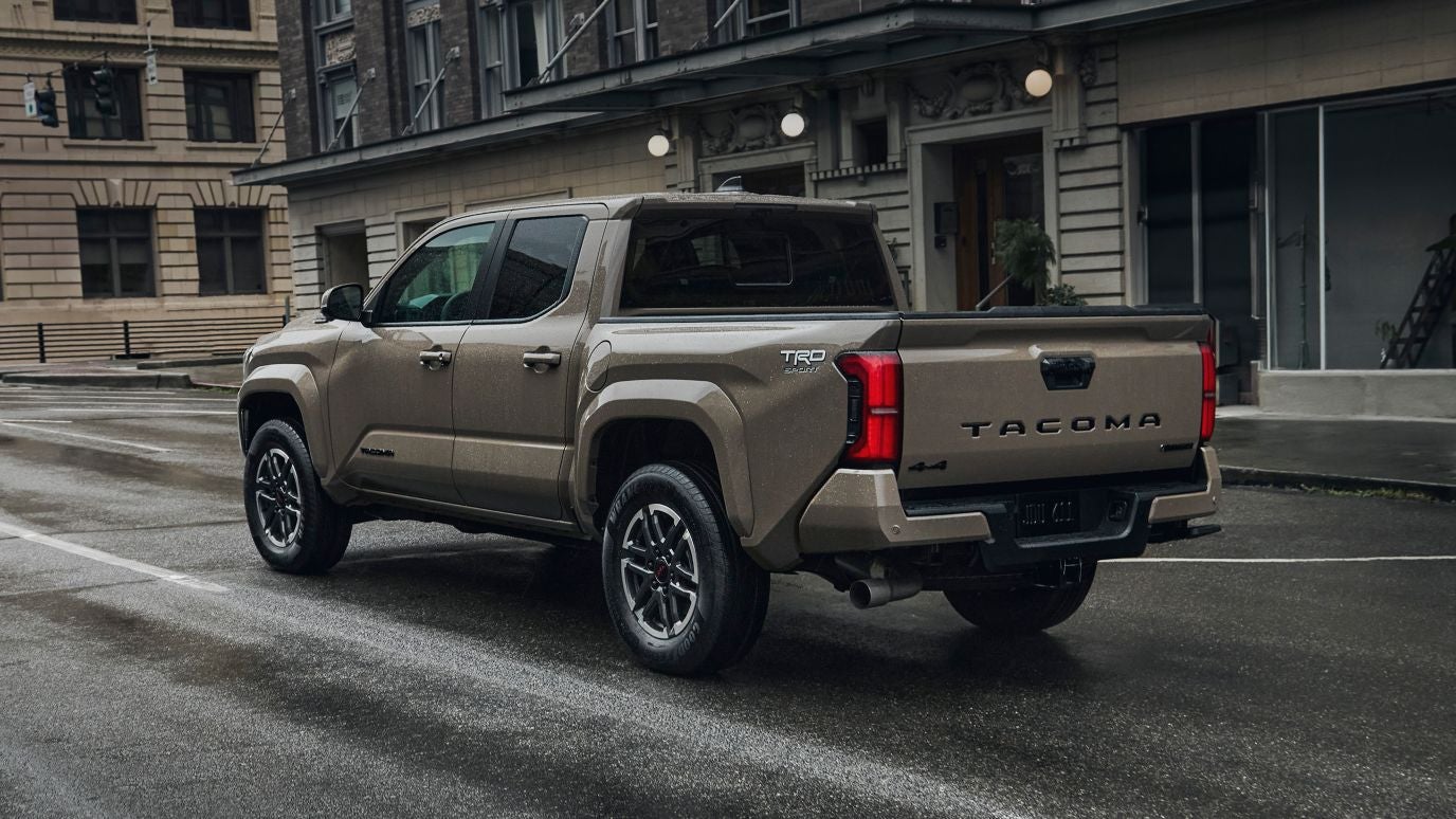 A brown Toyota Tacoma driving through a city
