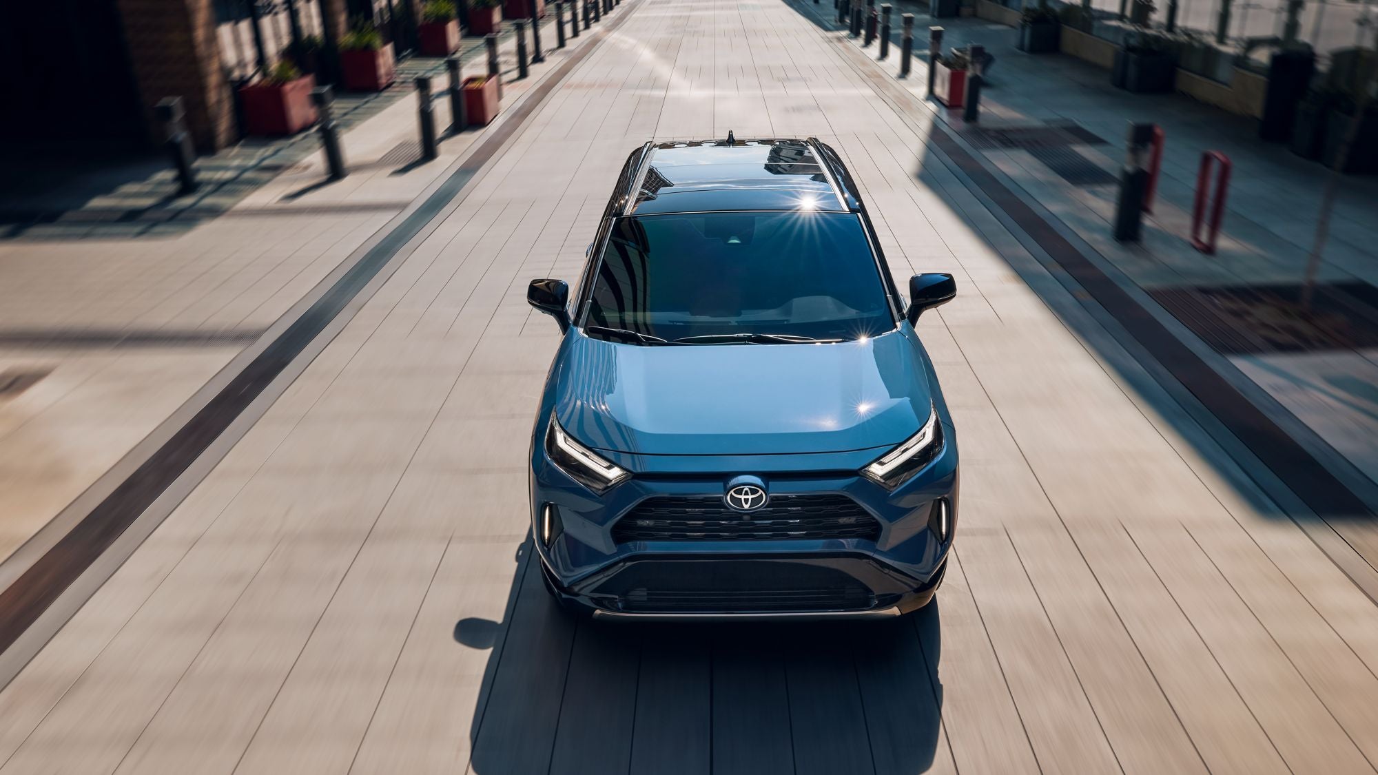 An overheard image of a blue Toyota RAV4 Hybrid driving through a city